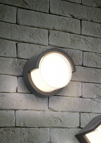 Round outdoor wall light fixture on a stone wall