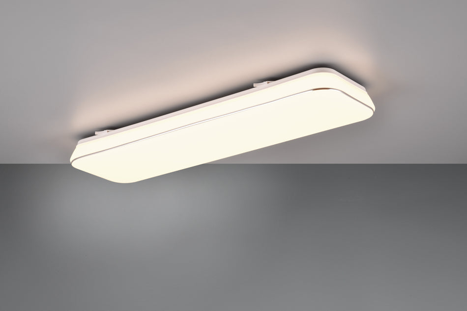 A white, rectangular LED ceiling light fixture mounted on a ceiling, emitting a warm white light.