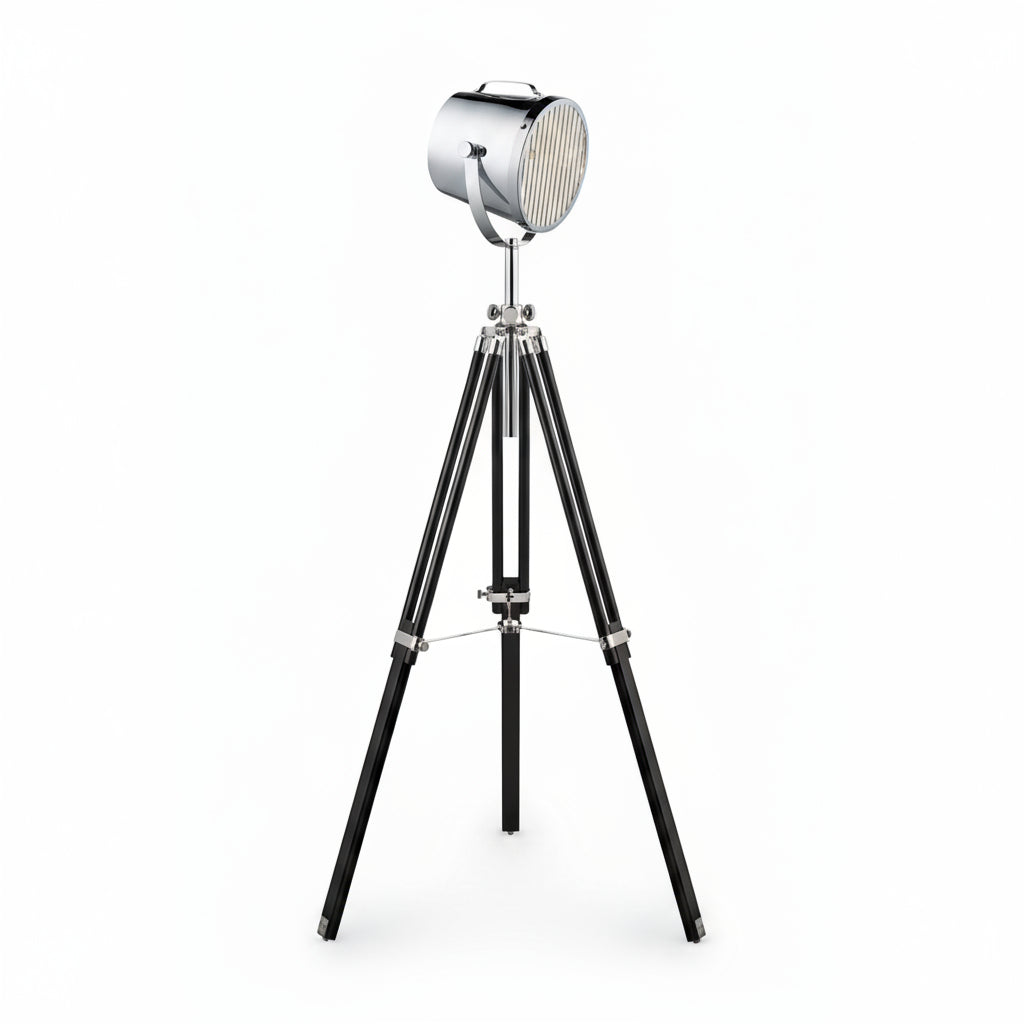 A studio tripod floor lamp with a chrome metal shade and black wood base.