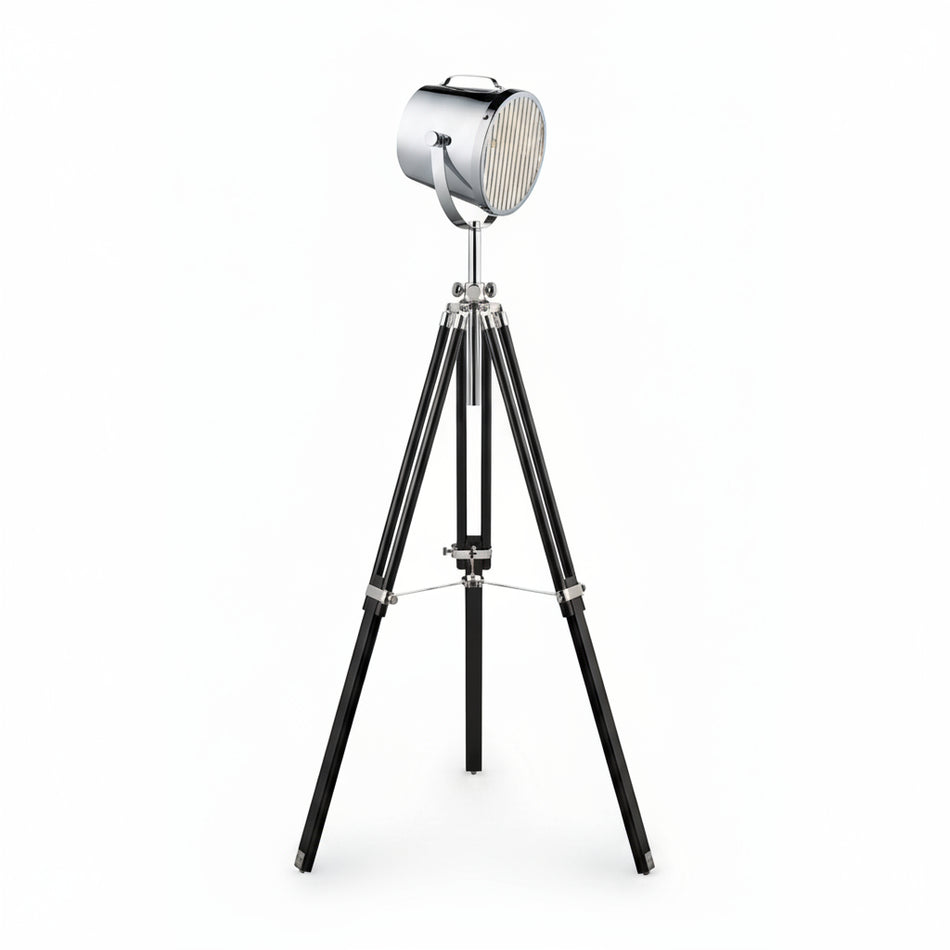 A studio tripod floor lamp with a chrome metal shade and black wood base.